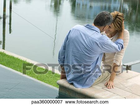 Couple sitting by edge of water View Large Photo Image Stock Photo - Couple sitting by edge of water. Fotosearch
