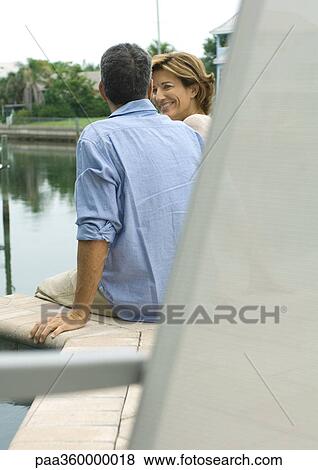 Stock Photo - Couple sitting by edge of water. Fotosearch