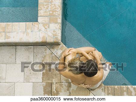 Stock Photography - Couple sitting on edge of pool together. Fotosearch