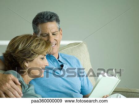 Mature couple looking at book together View Large Photo Image Stock Photo - Mature couple looking at book together. Fotosearch