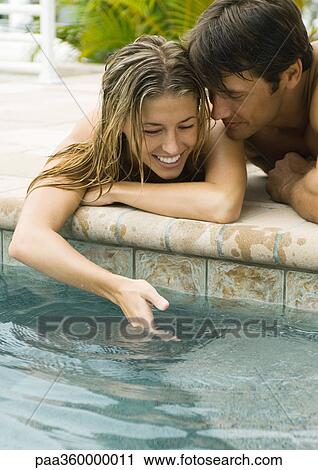 Young couple lying by edge of pool, woman dipping hand into water View Large Photo Image Stock Image - Young couple lying by edge of pool, woman dipping hand into water. Fotosearch
