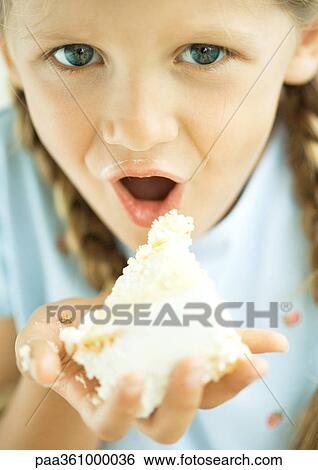 Stock Photograph - Girl eating piece of cake with hand. Fotosearch