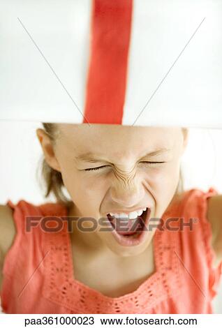 Girl making face, holding present on head View Large Photo Image Stock Image - Girl making face, holding present on head. Fotosearch