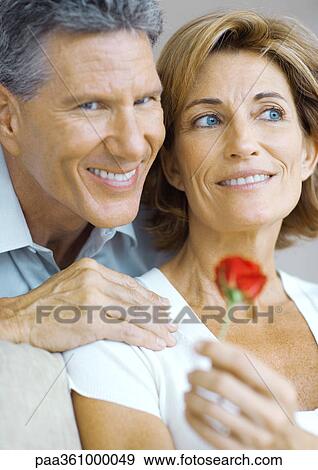 Stock Photo - Mature couple, woman holding rose bud. Fotosearch