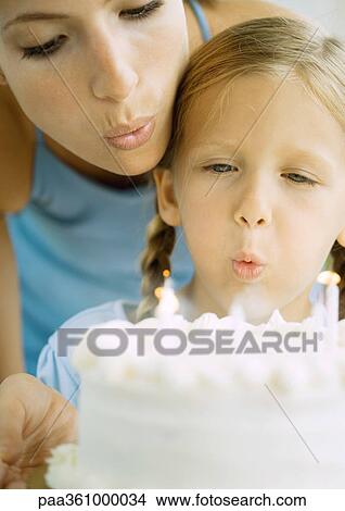 Mother and girl blowing out candles on birthday cake View Large Photo Image Picture - Mother and girl blowing out candles on birthday cake. Fotosearch