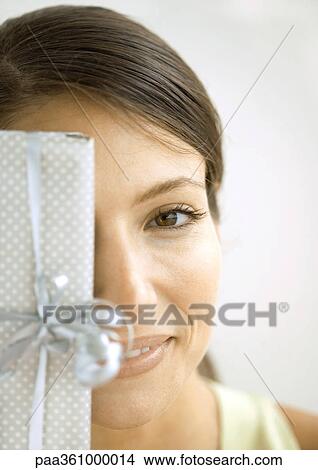 Woman holding gift in front of face View Large Photo Image Picture - Woman holding gift in front of face. Fotosearch