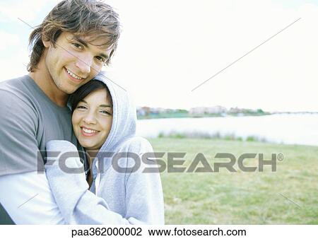 Stock Image - Young couple cuddling outdoors. Fotosearch
