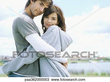 Young couple embracing outdoors View Large Photo Image Stock Image - Young couple embracing outdoors. Fotosearch