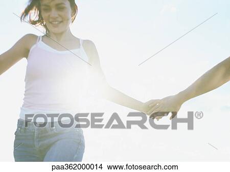 Young couple holding hands, smiling View Large Photo Image Picture - Young couple holding hands, smiling. Fotosearch