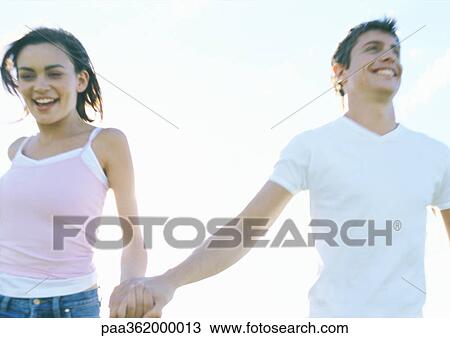 Young couple holding hands, smiling View Large Photo Image Stock Image - Young couple holding hands, smiling. Fotosearch