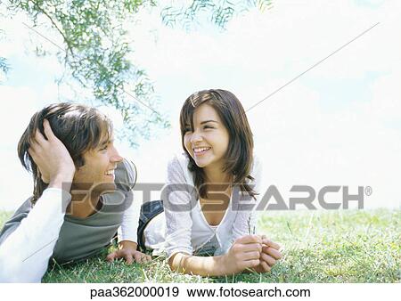 Stock Photo - Young couple lying on grass . Fotosearch