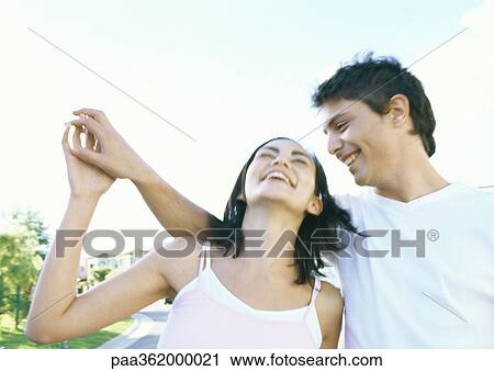 Young couple outdoors, laughing View Large Photo Image Stock Image - Young couple outdoors, laughing. Fotosearch