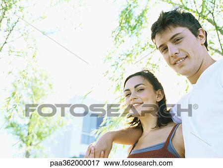 Young couple outdoors, smiling at camera View Large Photo Image Stock Photo - Young couple outdoors, smiling at camera. Fotosearch