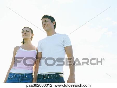 Young couple walking outdoors, front view View Large Photo Image Stock Image - Young couple walking outdoors, front view. Fotosearch