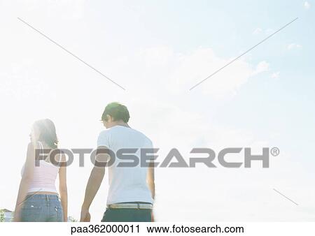 Young couple walking outdoors, rear view View Large Photo Image Stock Image - Young couple walking outdoors, rear view. Fotosearch