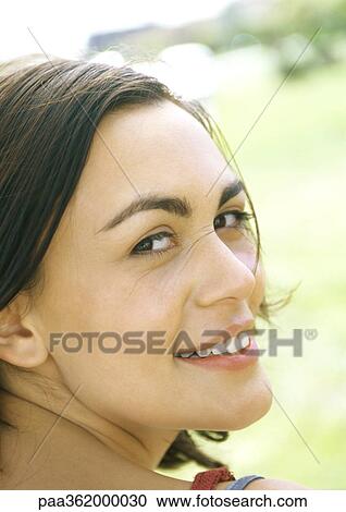 Young woman, looking over shoulder, smiling at camera View Large Photo Image Stock Image - Young woman, looking over shoulder, smiling at camera. Fotosearch