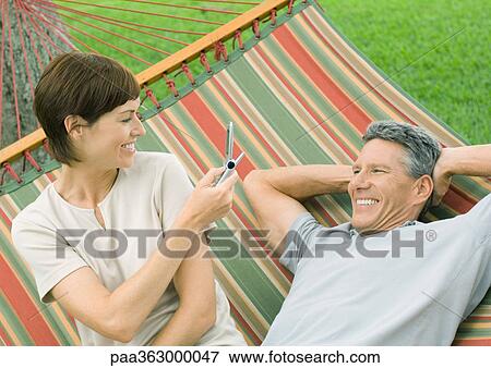 Couple in hammock, woman taking photo of man, with phone View Large Photo Image Stock Photo - Couple in hammock, woman taking photo of man, with phone. Fotosearch