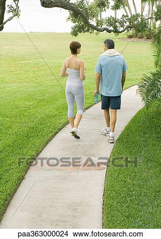 Couple in workout clothes walking on walkway, rear view View Large Photo Image Picture - Couple in workout clothes walking on walkway, rear view. Fotosearch