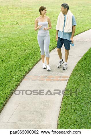 Mature couple walking on sidewalk in workout clothes View Large Photo Image Stock Image - Mature couple walking on sidewalk in workout clothes. Fotosearch
