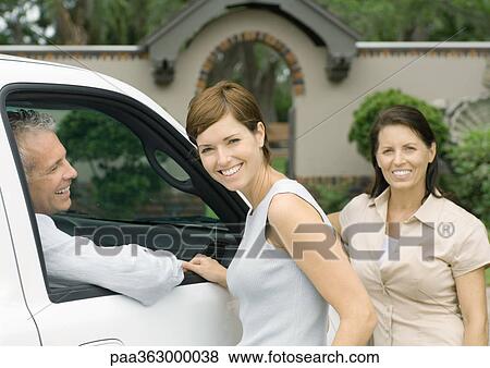 Two women standing next to vehicle with man inside, smiling View Large Photo Image Stock Photo - Two women standing next to vehicle with man inside, smiling. Fotosearch