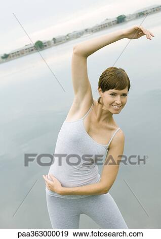 Woman doing stretches by edge of water View Large Photo Image Stock Photo - Woman doing stretches by edge of water. Fotosearch