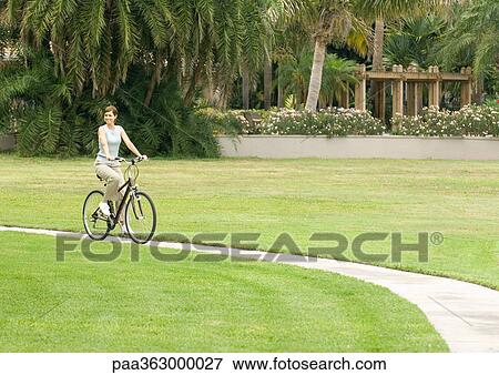 Woman riding bike on walkway View Large Photo Image Stock Photo - Woman riding bike on walkway. Fotosearch