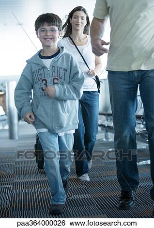 Boy walking through airport with parents, smiling View Large Photo Image Stock Photograph - Boy walking through airport with parents, smiling. Fotosearch