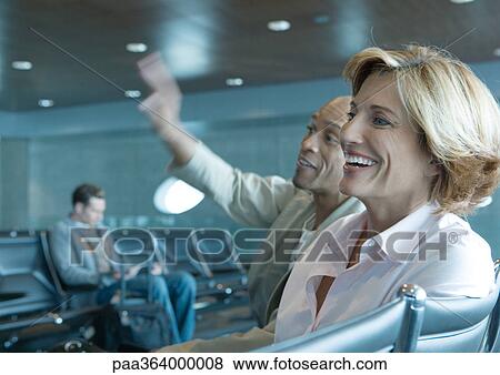 Man and woman sitting in airport lounge, laughing View Large Photo Image Stock Photo - Man and woman sitting in airport lounge, laughing. Fotosearch
