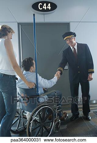 Man in wheelchair shaking hands with pilot in airport View Large Photo Image Stock Image - Man in wheelchair shaking hands with pilot in airport. Fotosearch