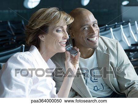 Travelers sharing cell phone in airport lounge View Large Photo Image Stock Image - Travelers sharing cell phone in airport lounge. Fotosearch