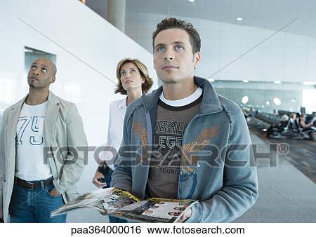 Travelers standing in airport, looking up View Large Photo Image Stock Photograph - Travelers standing in airport, looking up. Fotosearch