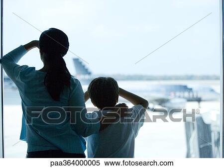 Woman and boy looking through window in airport View Large Photo Image Stock Photography - Woman and boy looking through window in airport. Fotosearch