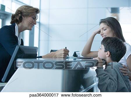 Woman and son standing at check-in counter in airport View Large Photo Image Stock Photo - Woman and son standing at check-in counter in airport. Fotosearch