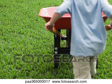 Boy pushing wheelbarrow, rear view View Large Photo Image Stock Photo - Boy pushing wheelbarrow, rear view. Fotosearch