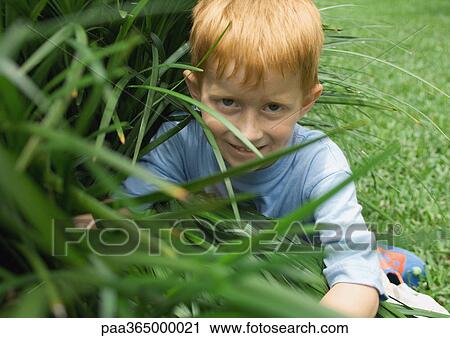 Stock Image - Boy sitting in long grass. Fotosearch