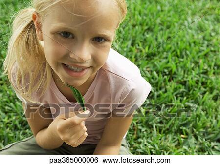 Stock Photograph - Girl holding leaf under chin. Fotosearch