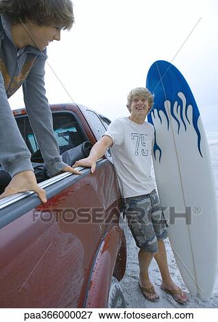 Stock Photo - Surfer standing next to pickup truck. Fotosearch