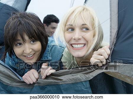 Two young female friends looking out of tent View Large Photo Image Stock Image - Two young female friends looking out of tent. Fotosearch