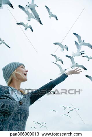 Woman holding arm up to sky where seagulls are flying View Large Photo Image Stock Image - Woman holding arm up to sky where seagulls are flying. Fotosearch