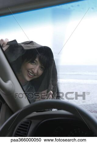 Woman holding jacket over head, looking through car windshield View Large Photo Image Stock Image - Woman holding jacket over head, looking through car windshield. Fotosearch