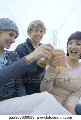 Young adult friends clinking beer bottles View Large Photo Image Stock Image - Young adult friends clinking beer bottles. Fotosearch