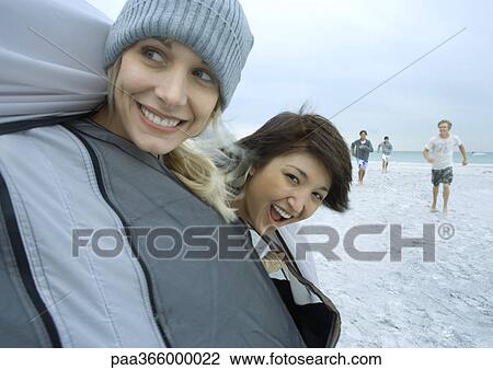 Stock Image - Young adult friends looking out of tent on beach. Fotosearch