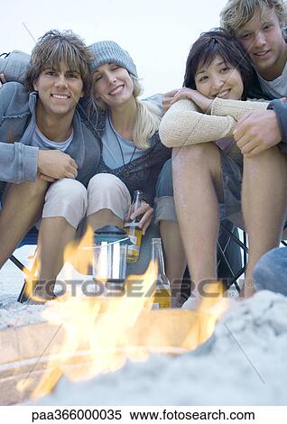 Young adult friends sitting around campfire View Large Photo Image Stock Photography - Young adult friends sitting around campfire. Fotosearch