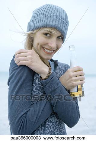 Young woman holding beer bottle on beach View Large Photo Image Stock Image - Young woman holding beer bottle on beach. Fotosearch