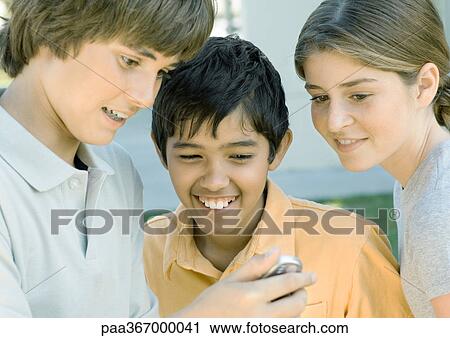 Preteen friends looking at cell phone View Large Photo Image Stock Image - Preteen friends looking at cell phone. Fotosearch