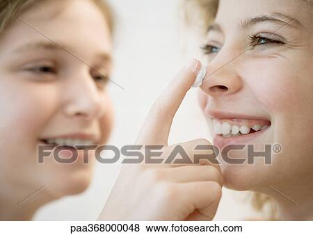 Girl putting lotion on friend's nose View Large Photo Image Stock Photo - Girl putting lotion on friend's nose. Fotosearch