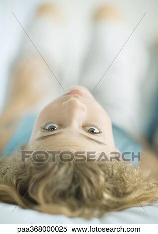 Stock Photography - Preteen girl lying on back, looking at camera. Fotosearch