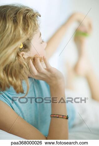 Stock Photograph - Preteen girl lying on stomach, reaching back for foot. Fotosearch