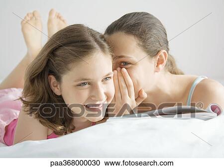 Preteen girl whispering to friend View Large Photo Image Stock Image - Preteen girl whispering to friend. Fotosearch