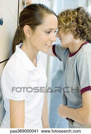 Teen boy whispering to teen girl, next to lockers View Large Photo Image Stock Image - Teen boy whispering to teen girl, next to lockers. Fotosearch